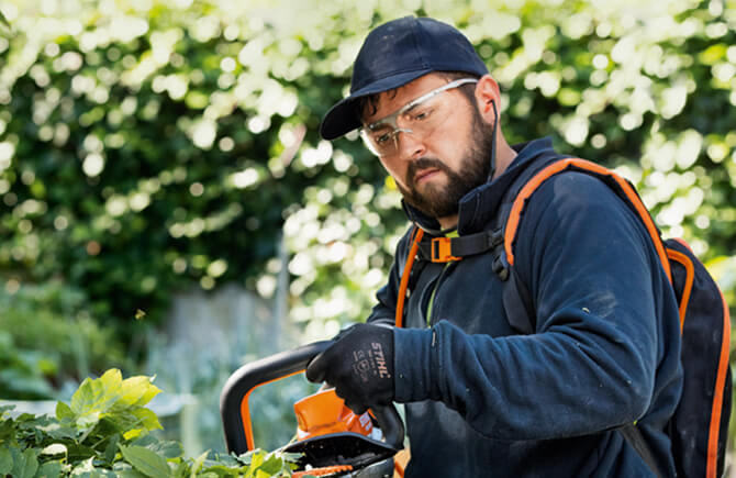Eine Schutzbrille von STIHL verhindert schwerwiegende Verletzungen des Auges durch umherfliegende Teilchen. Schutzbrille von STIHL beim Einsatz mit der Heckenschere